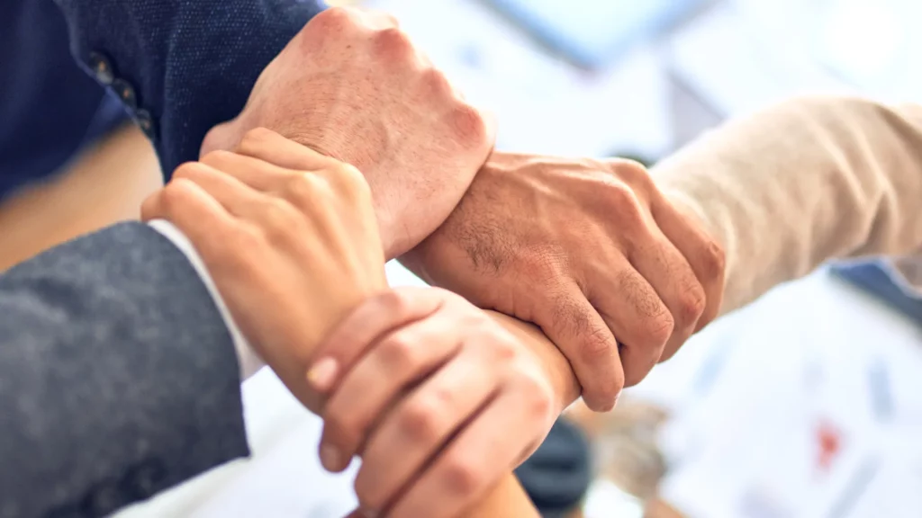 Image of four people's hands clasped in a chain