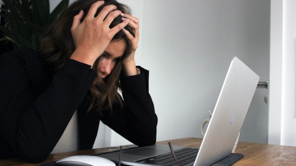 Business licensing services Frustrated woman holding her head in front of a notebook
