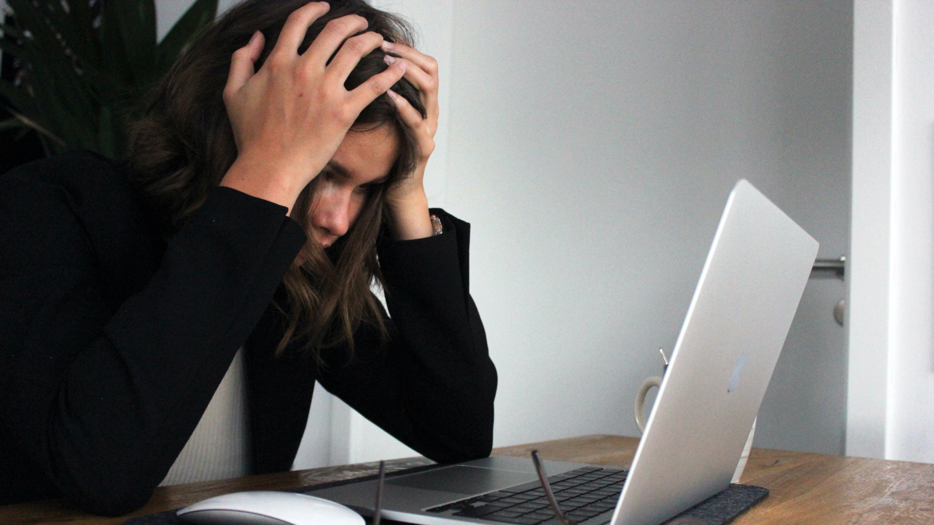 frustrated woman holding head in hands in front of hear notebook