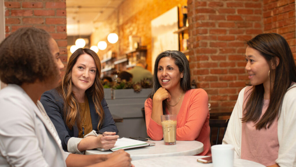 four woman chatting around a table